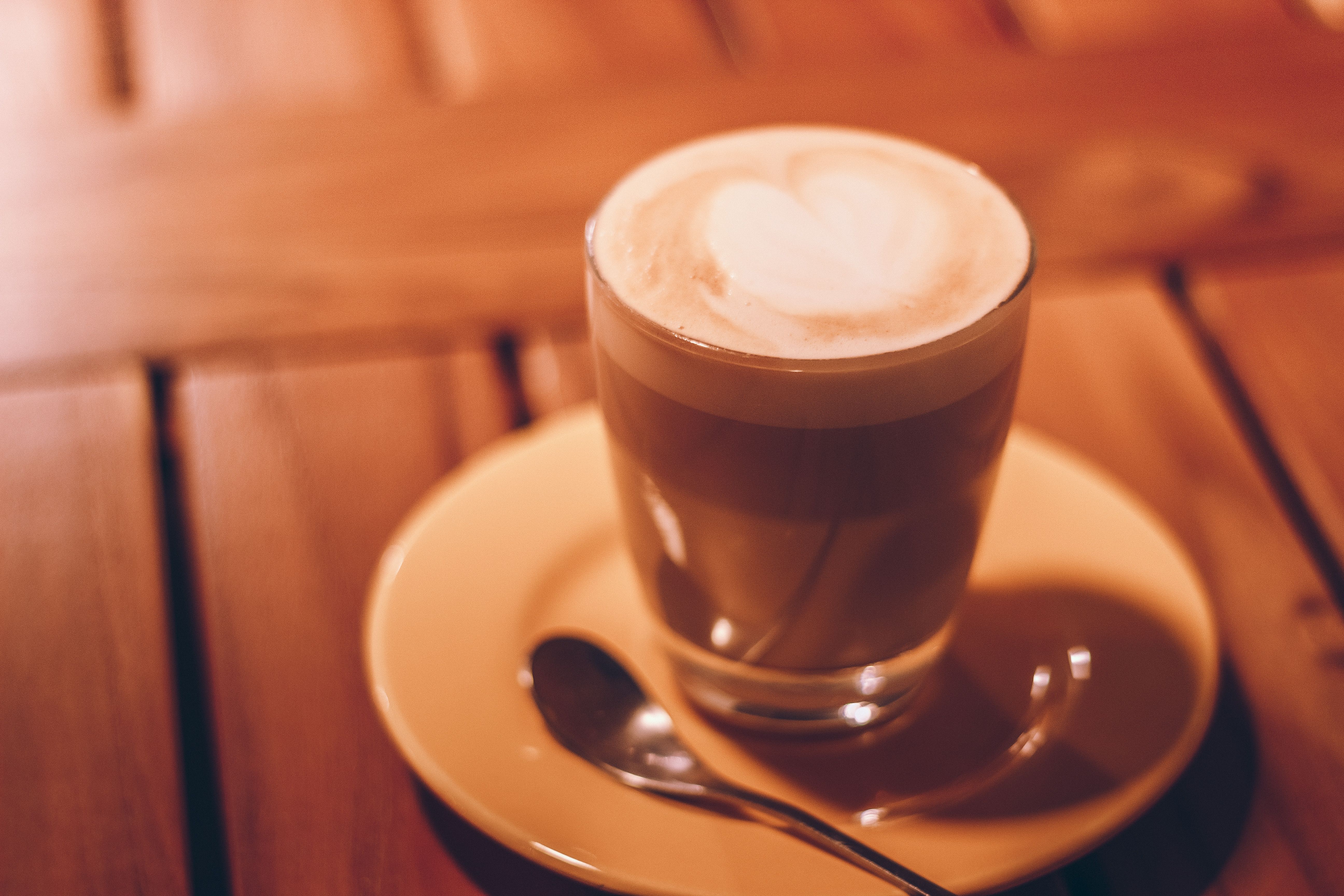 Glas Milchkaffee mit Herz-Muster auf einem Holztisch