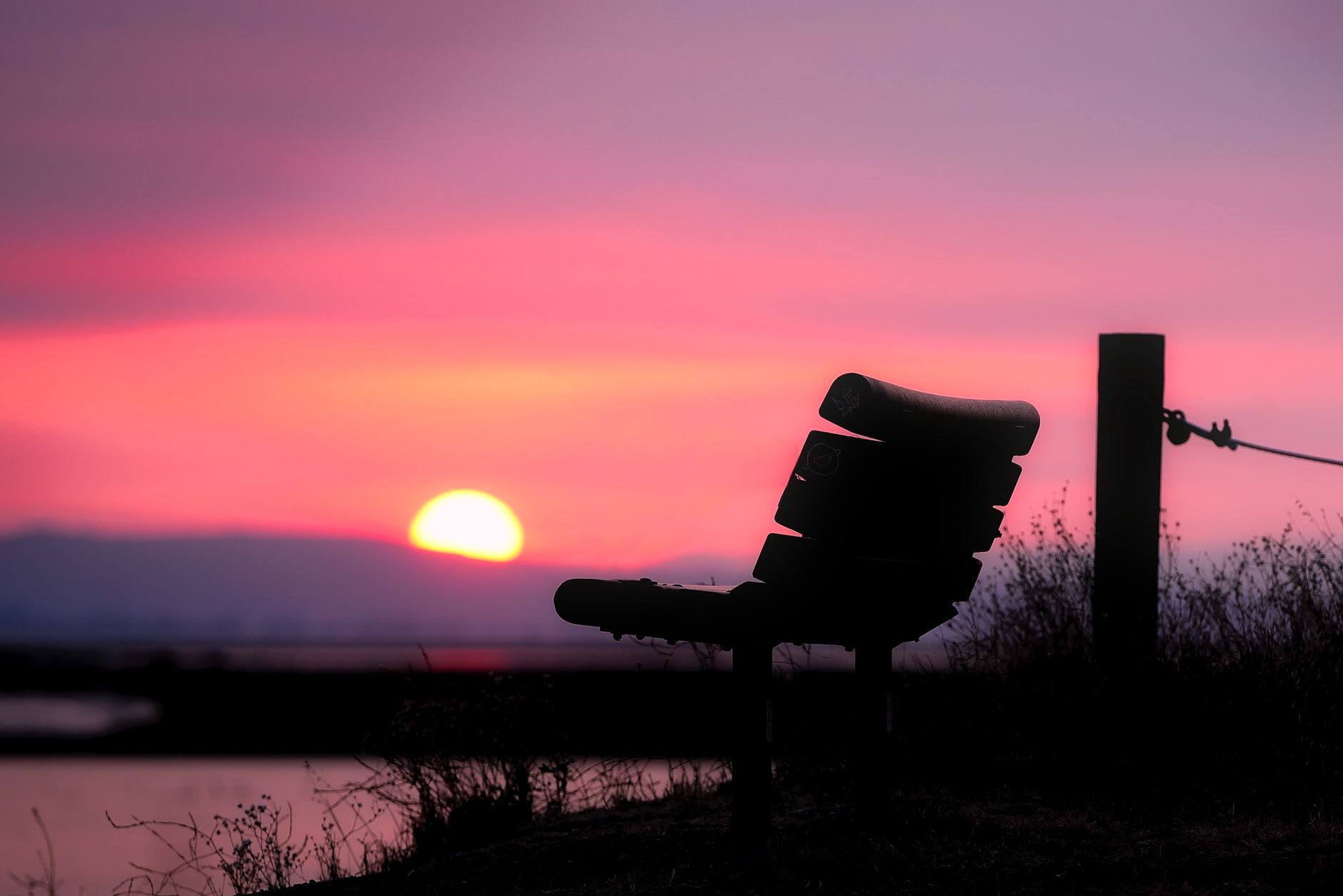 Serene Silhouette einer Bank, die einem schönen Sonnenuntergangshimmel zugewandt ist, und Entspannung sowie Frieden heraufbeschwört.