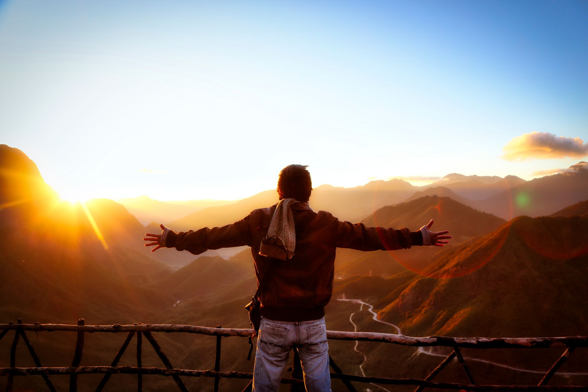 Silhouette einer Person, die den malerischen Sonnenuntergang über den Bergen in Tam Đường, Vietnam, umarmt.