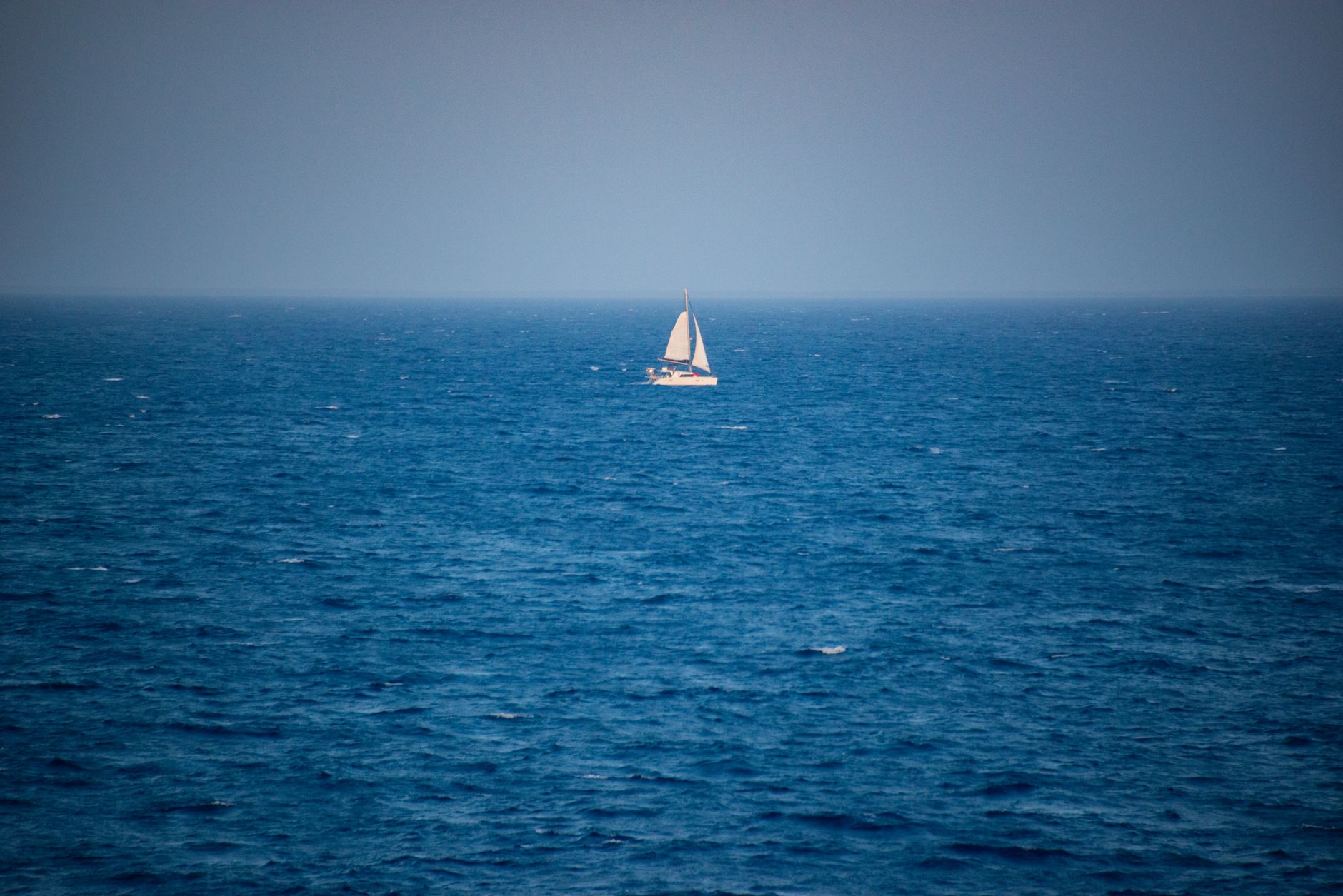 Ein einsames Segelboot fährt über die ruhigen blauen Meere und fängt die Essenz maritimer Abenteuer ein.