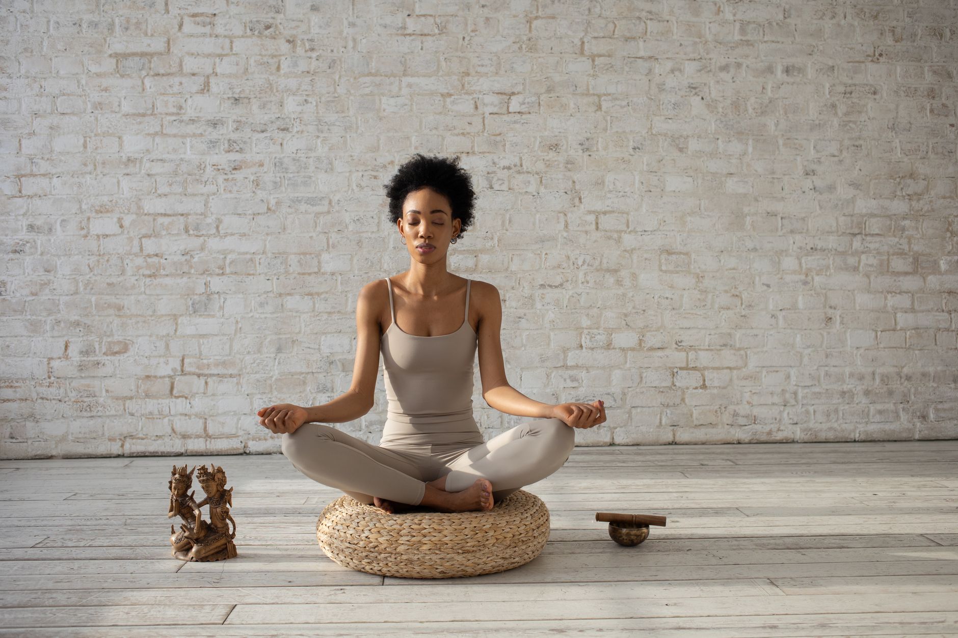 Frau praktiziert Yoga-Meditation auf einem Kissen drinnen und umarmt Frieden und Wohlbefinden.