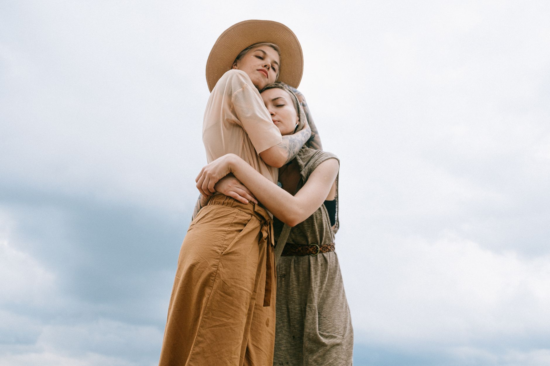 Zwei Frauen teilen eine tröstende Umarmung im Freien, die Liebe und Zusammengehörigkeit symbolisiert.