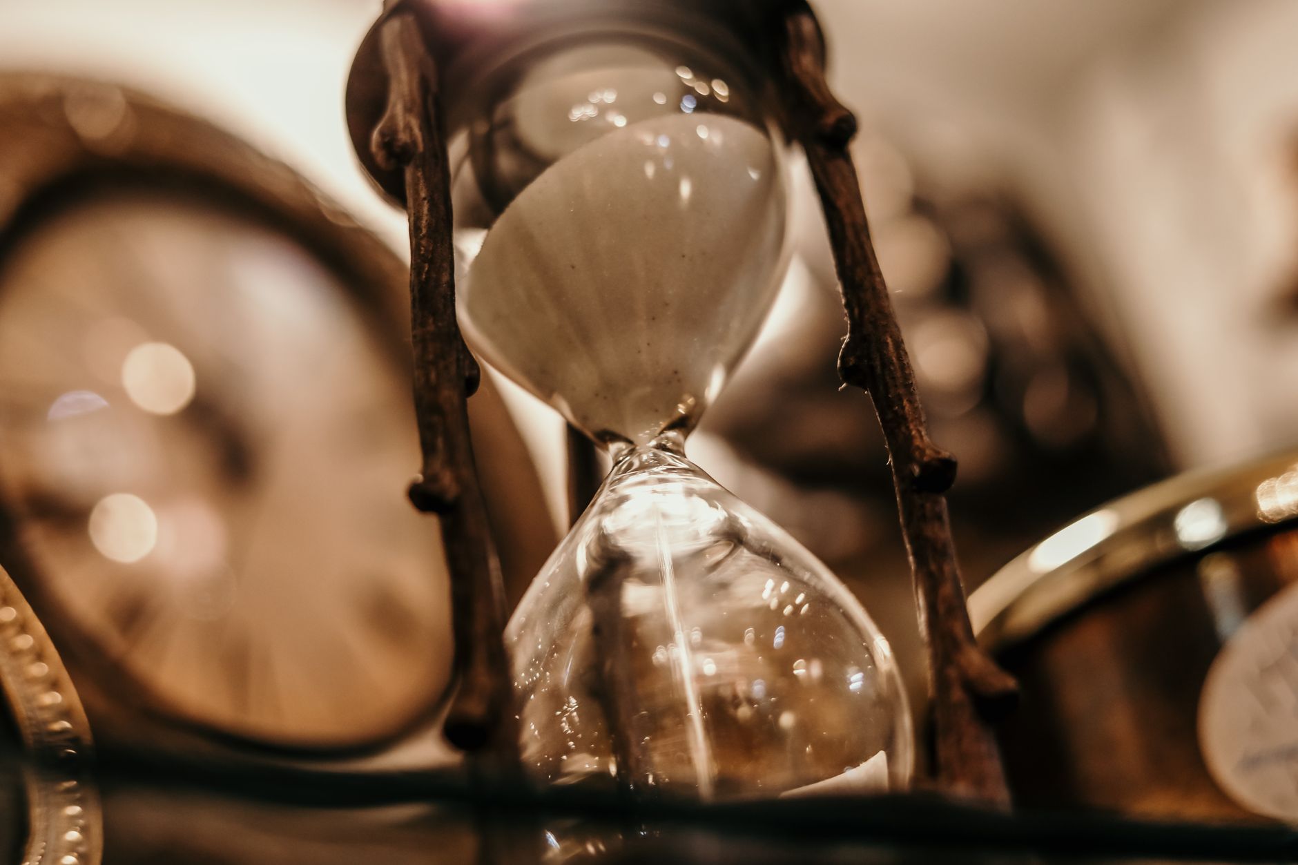 Nahaufnahme einer vintage Sanduhr mit unscharfem Hintergrund eines antiken Uhren, das ein zeitloses Gefühl vermittelt.