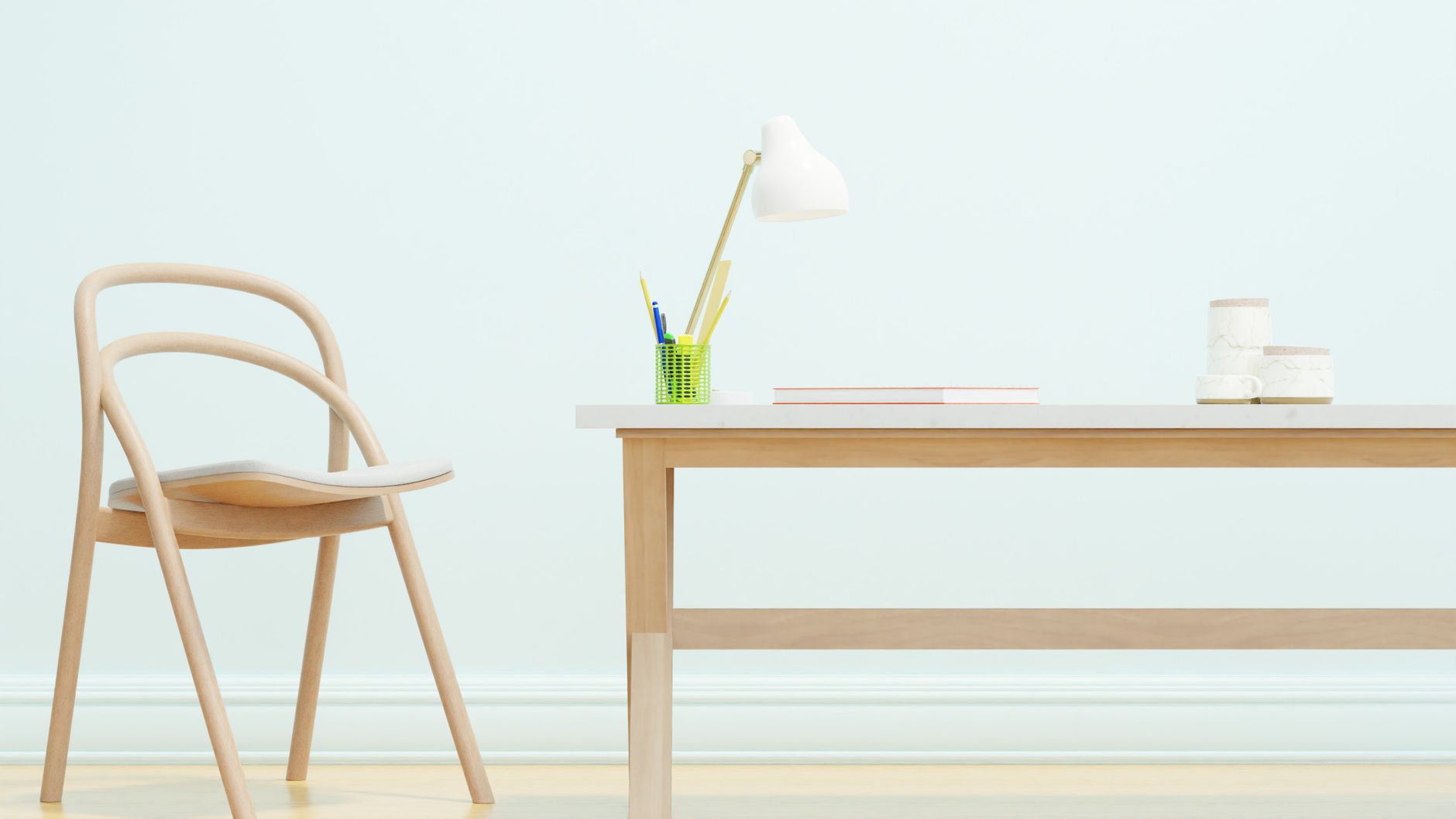 Ein minimalistischer Arbeitsplatz mit einem Holzstuhl und -tisch, einem weißen Lampenschirm und Büromaterial.